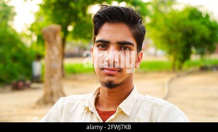 Porträt eines gesunden jungen Mannes, der im Park sitzt und die Kamera anschaut. Stockfoto