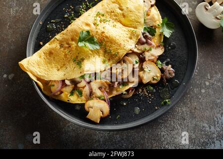 Von oben appetitliches Omelett mit Pilzen und Kräutern bestreut Mit Gewürzen auf dem Teller auf dem Tisch serviert Stockfoto