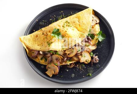 Hoher Winkel von schmackhaften Omelette mit Pilzen und Kräutern serviert Auf Platte auf weißem Hintergrund Stockfoto