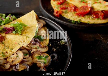 Hoher Winkel von Tellern mit leckeren Omelettes mit Pilzen und Tomaten auf dem Tisch serviert Stockfoto