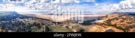 Bundesautobahn entlang des Lake George in NSW von Australien mit entferntem Windturbinenpark - breites Luftpanorama. Stockfoto