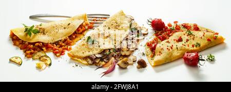 Von oben köstliche Omelettes mit Gemüse und Pilzen Serviert auf weißem Hintergrund Stockfoto