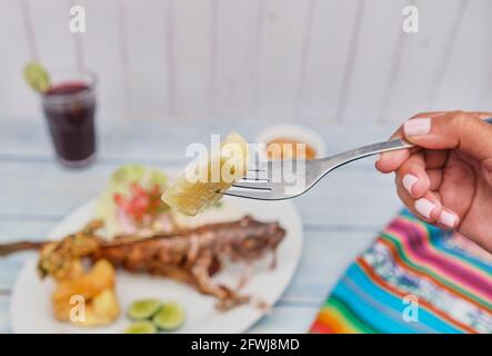Frau mit gebratenem Yucca, peruanische Küche: Cabrilla Frita, gebratener Fisch. Selektiver Fokus Stockfoto