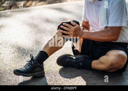 Nahaufnahme eines älteren Mannes, der während des Trainings im Park an Knieschmerzen litt. Stockfoto