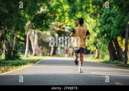 Rückansicht des jungen Mannes Joggen oder Laufen Training im Freien im Park, Konzept eines gesunden Lebensstils. Stockfoto