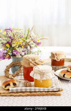 Gläser mit Honig und Strauß von wilden Blumen auf dem Tisch. Gesunde Ernährung Stockfoto