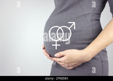 Mittelteil der Schwangeren Frau berührt Bauch mit Hologramm männlichen und weiblichen Geschlechts-Symbol von Grey Background. Vorbereitung und Erwartung Konzept. Schließen Stockfoto