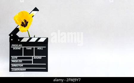 Klappbrett aus Film mit gelber Tulpe. Minimale Standzeit der Klapptafel für die Herstellung von Video-Kino und Frühlingsblumen. Stockfoto