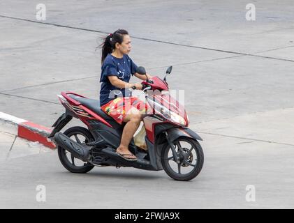 SAMUT PRAKAN, THAILAND, JULI 25 2020, EINE Frau fährt auf einer Straße mit dem Motorrad Stockfoto