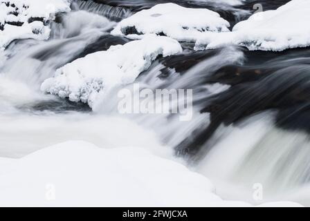 Wasser läuft auf eisigem Fluss Stockfoto