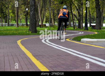 Ein Mann fährt mit dem Fahrrad auf einem Radweg in einem Park. Stockfoto