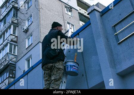 Dnepropetrovsk, Ukraine - 03.29.2021: Das Werk des Malers steht an der Spitze. Ein Mitarbeiter malt die Fassade eines Gebäudes, während er auf der Treppe steht. Stockfoto