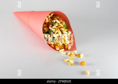 Scharf würziger Puffreis in rosa Papier. Traditionelle beliebte Armreif und indischen Abendpark Snacks. Zutaten Mischung sind Chanachur, Erdnuss, Minze. Stockfoto