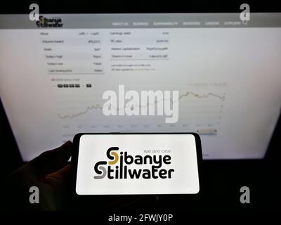 Person, die Smartphone mit dem Logo des südafrikanischen Bergbauunternehmens Sibanye Stillwater Limited auf dem Bildschirm vor der Webseite hält. Konzentrieren Sie sich auf die Telefonanzeige. Stockfoto