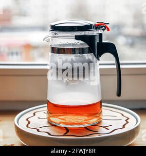 Teekannen aus Kunststoff-Glas mit Knopf und Kolben zum Brühen von Tee Brühen Stockfoto