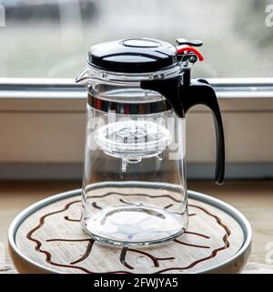 Teekannen aus Kunststoff-Glas mit Knopf und Teeflasche. Stockfoto