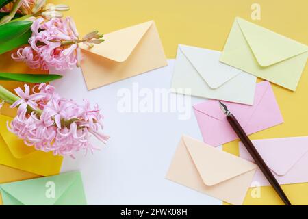 Bunte Umschläge und Hyazinthen-Blumen auf gelbem Hintergrund, Kopierraum. Stockfoto