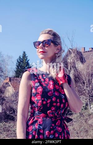 Portrait einer blonden Frau in rotem Kleid und Sonnenbrillen genießen Die Sonne Stockfoto