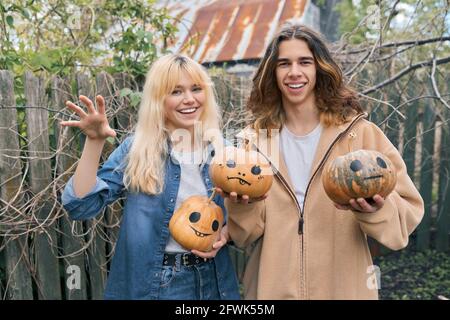 Ein paar lachende Teenager mit halloween-Kürbissen, die Spaß haben Stockfoto