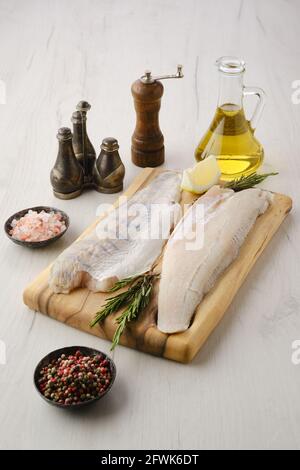 Rohes Zanderfilet auf Holzschneidebrett mit Gewürzen Stockfoto