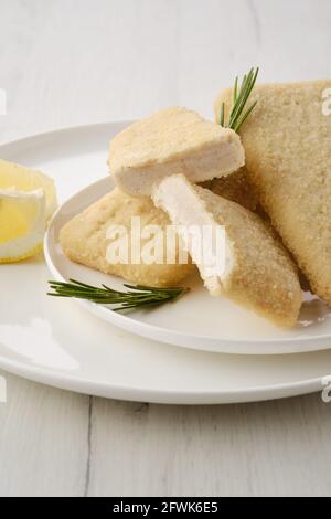 Gefrorenes halbfertiges Tintenfischpastete in der Panade auf dem Küchentisch Stockfoto