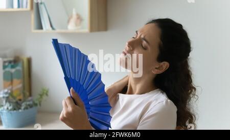Überhitzt gestresste tausendjährige Frau winkende Papierfächer. Stockfoto