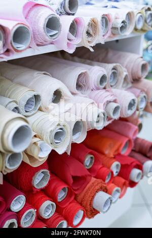 Online- oder Offline-Verkauf, Schneiderei- oder Dachateliterkonzept. Nahaufnahme-Stoffe Rollen in den Farben Rot, Rosa und Beige. Textileinzelhandel, Draperie oder Textilgeschäft. Hochwertiges vertikales Bild Stockfoto
