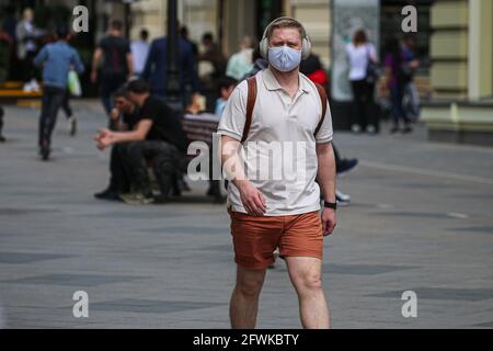 Moskau, Russland. Mai 2021. Ein Mann mit Schutzmaske geht am 23. Mai 2021 in Moskau, Russland, spazieren. Die kumulative Zahl der COVID-19-Fälle in Russland erreichte 5,001,505, nachdem das Land in den letzten 24 Stunden 8,951 neue Infektionen registriert hatte, teilte das offizielle Überwachungs- und Reaktionszentrum am Sonntag mit. Quelle: Evgeny Sinitsyn/Xinhua/Alamy Live News Stockfoto