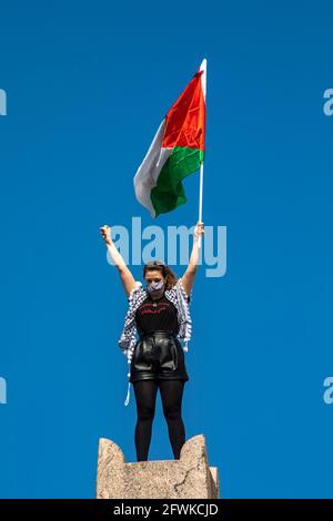 Junge Frau mit einer Gesichtsmask, die die Flagge Palästinas schwenkt, beim solidaritätsmarsch im Namen Palästinas in Helsinki, Finnland Stockfoto