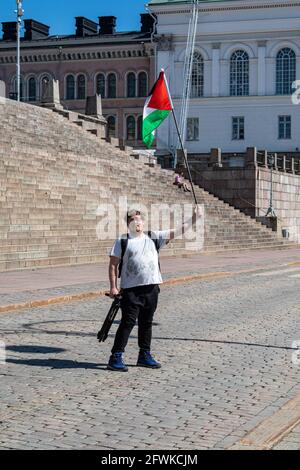 Männlicher Protestler, der die Flagge Palästinas auf dem Senatsplatz schwenkte, bevor er im Namen Palästinas in Helsinki, Finnland, einen Solidaritäts-Marsch durchmarschierte Stockfoto