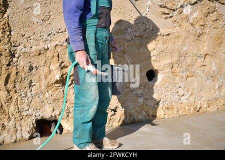 Der Maurer gießt frischen Beton, der auf die Grundsteinmauer gegossen wird Stockfoto