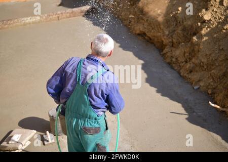 Der Maurer gießt frischen Beton, der auf die Grundsteinmauer gegossen wird Stockfoto
