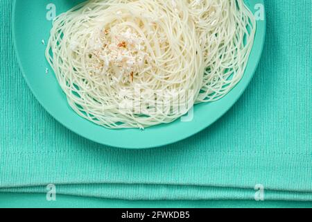 Ideyappam oder Noolappam, südindisches Frühstück, das wunderschön arrangiert ist Mit zwei Scheiben gekochter Eier in aquamarinfarbener Farbe Tafelgeschirr pla Stockfoto