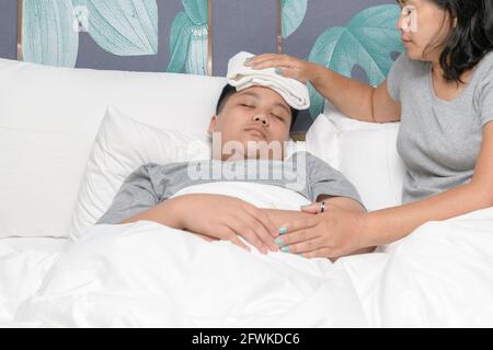 Asiatische Mutter wischte den Körper des Sohnes, um Fieber im Schlafzimmer, Konzept der Liebe und gesunde Versorgung im Familienleben zu reduzieren. Stockfoto