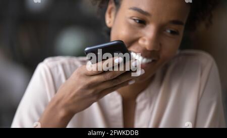 Glückliche junge afro brasilianische Frau Aufnahme Sprachnachricht. Stockfoto