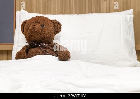 Einsamer Teddybär, der auf dem Bett liegt. Konzept über das Warten auf jemanden und Einsamkeit. Stockfoto