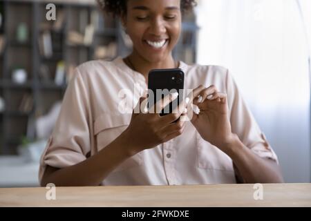 Lächelnde junge afrikanische Frau mit Smartphone in Innenräumen. Stockfoto