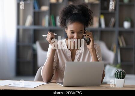 Lächelnd schöne tausendjährige afrikanische Geschäftsfrau Multitasking im Büro. Stockfoto
