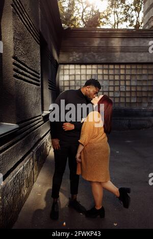 Porträt eines schönen afroamerikanischen Mannes, der in der Nähe des Hauses in der Stadt eine wunderschöne weiße Frau küsst, liebevoller Ehemann mit schöner Frau, der Zeit verbringt Stockfoto