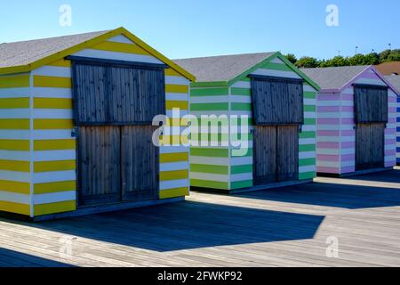 Staycation Idee. Nahaufnahme von bunt gestreiften Strandhütten-Ständen in einer Reihe am Hastings Pier, East Sussex, England, Großbritannien. Stockfoto