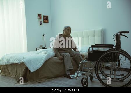 Der einsame alte Mann sitzt auf dem Bett Stockfoto