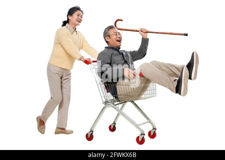 Ein glücklicher alter Mann schiebt seine Frau saß in der Warenkorb Stockfoto