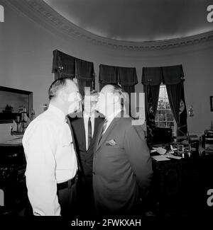 Präsident John F. Kennedy lacht während eines Besuchs mit dem Schauspieler und Komiker Bob Hope (rechts gegenüber dem Polizeibeamten des Weißen Hauses, dem Privatmann Robert Suggs, Jr.) im Oval Office des Weißen Hauses, Washington, D.C., besuchte Hope das Weiße Haus, um die Goldmedaille des Kongresses zu erhalten. Präsentiert von Präsident Kennedy in Anerkennung seiner Verdienste um das Land als Entertainer während des Zweiten Weltkriegs Stockfoto