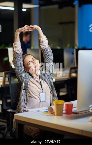 Müde junge Frau arbeitet im Nachtbüro Stockfoto