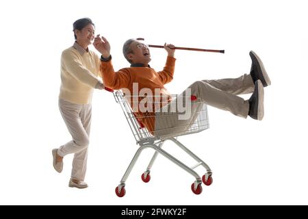 Ein glücklicher alter Mann schiebt seine Frau saß in der Warenkorb Stockfoto