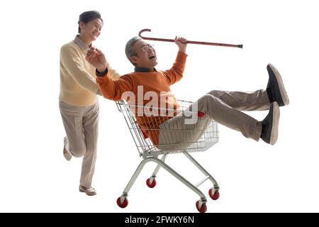 Ein glücklicher alter Mann schiebt seine Frau saß in der Warenkorb Stockfoto