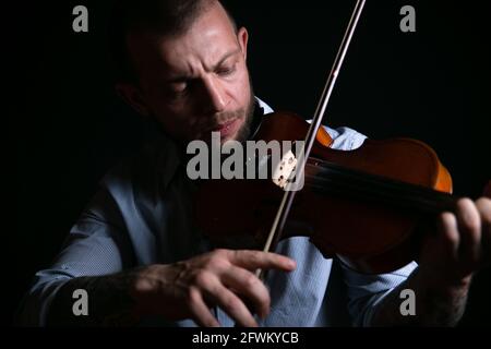 Meisterhaft spielt der männliche Geiger die Geige Stockfoto