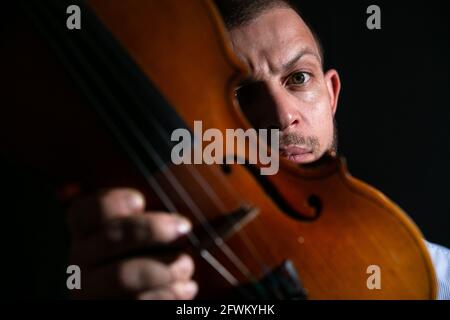 Porträt eines Geigers auf schwarzem Hintergrund mit einer Geige in den Händen. Stockfoto