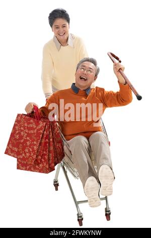 Ein glücklicher alter Mann schiebt seine Frau saß in der Warenkorb Stockfoto