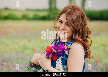 Nahaufnahme einer glücklichen und lächelnden Frau mit Lavendel Bouquet und stehen auf dem Feld voller wilder Blumen Stockfoto